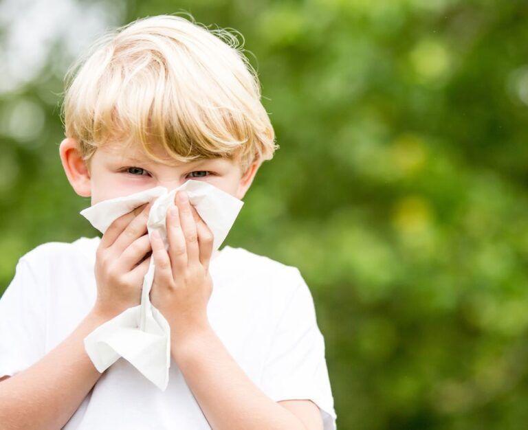 Банер до блогу для статті про синусит: хлопчик в білому одязі тримає велику білу серветку біля носа