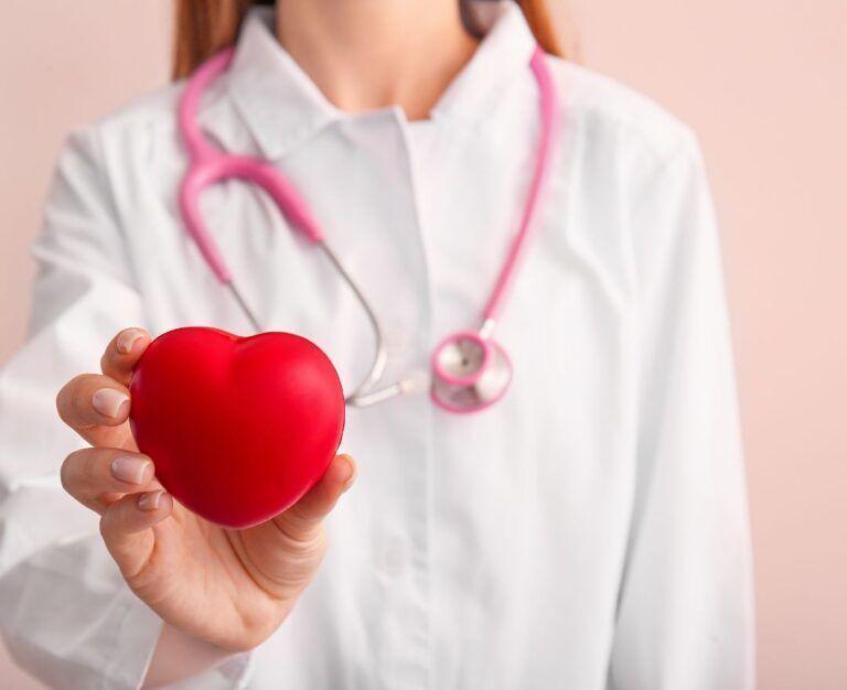 Банер для блогу до статті з підготовкою до кардіологічного чекапу: лікар в білому халаті і рожевим стетоскопом на шиї тримає червоне серце в руках