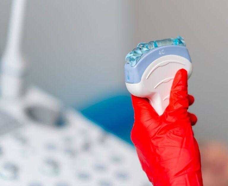 Банер до статті про підготовку до УЗ-скринінгу жіночого здоров'я: лікар УЗД в рукавицях червоного кольору тримає УЗД датчик у кабінеті Файної Клініки